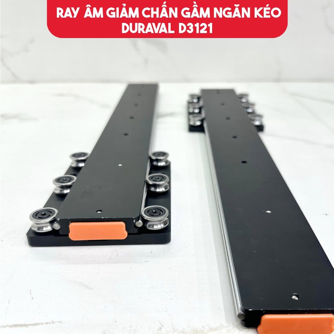 Cặp ray âm giảm chấn gầm ngăn kéo Duraval D3121 màu đen đặt trên mặt đá, có bánh xe và lẫy cài màu cam ở đầu ray