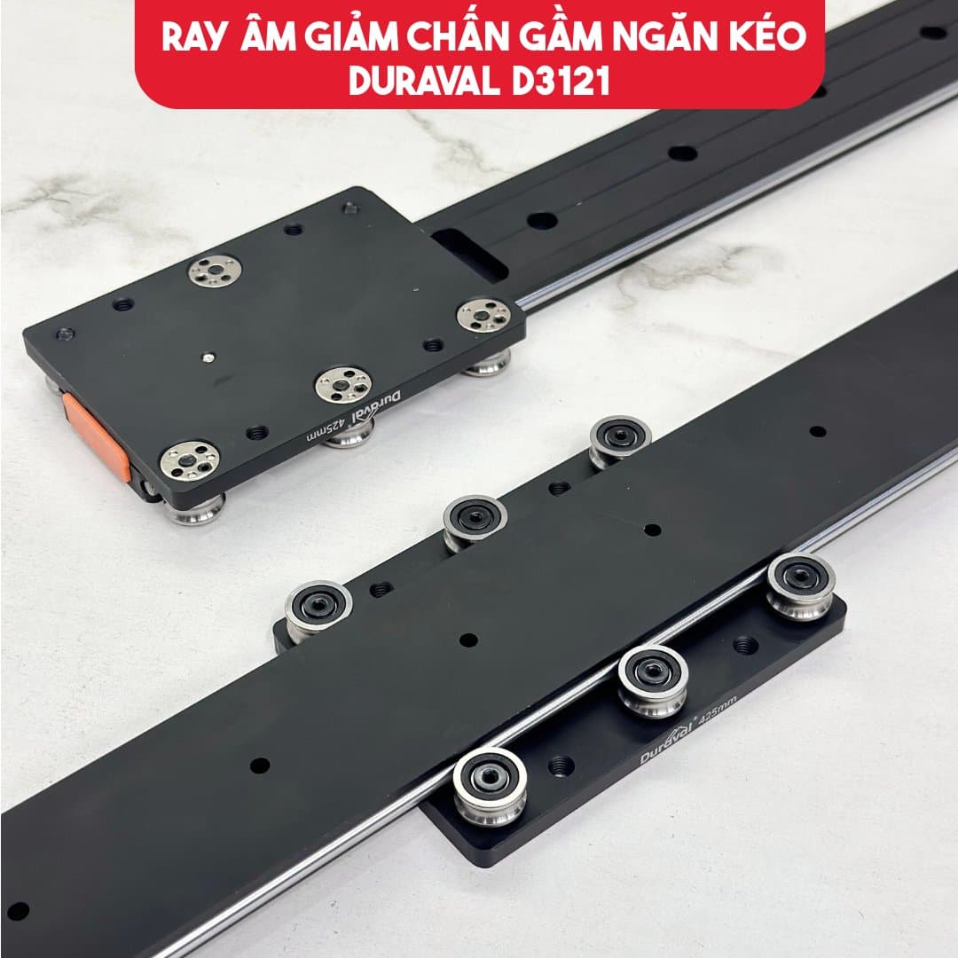 Cận cảnh ray âm giảm chấn gầm ngăn kéo Duraval D3121 màu đen, thấy hàng bánh xe chạy trên thanh ray và lẫy cài màu cam