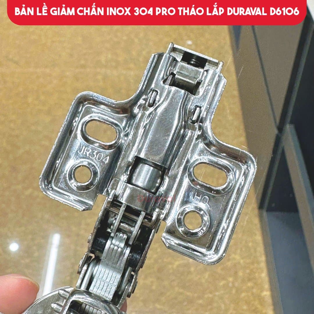 Cận tay bản lề giảm chấn Duraval D6106, thấy cụm piston giảm chấn nằm trong tay bản lề và đế inox 304