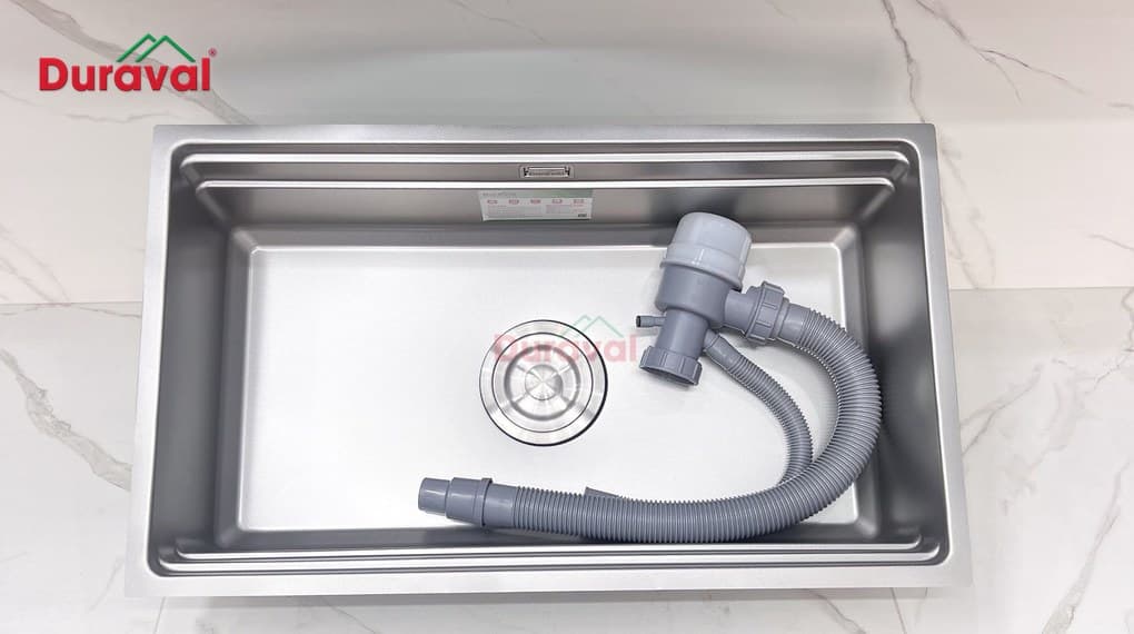 Chậu rửa 1 hố inox 304 Duraval D6608 đặt trên mặt đá trắng, kèm bộ xả và xi phông